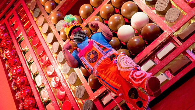 A man standing in front of a giant, red chocolate box full of chocolates