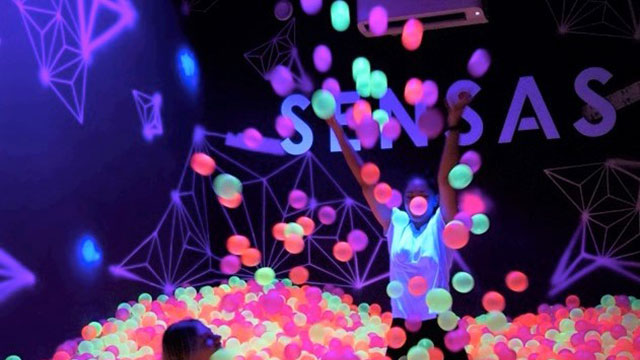 Two people playing in a ball pit full of multi-coloured balls at SENSAS