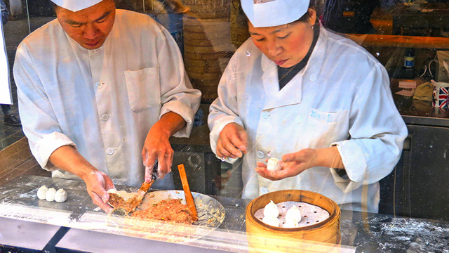 Two chefs make dumplings at Dumplings' Legend in London Chinatown.