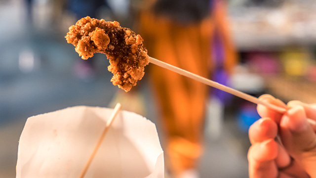 Hand holding a skewer of fried chicken at Good Friend in London Chinatown.