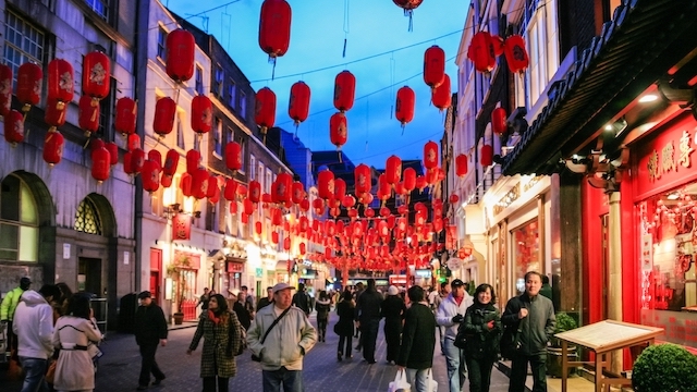 Red lanterns hang in the streets above London Chinatown at night.