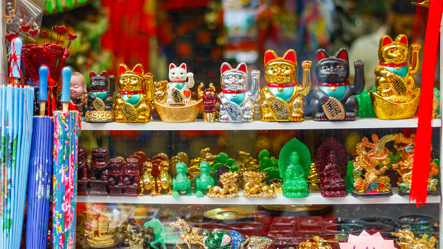 Lucky cats displayed on several shelves in London Chinatown shop window.