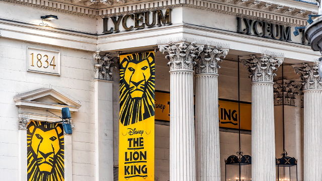 Lyceum Theatre building in London's Covent Garden with The Lion King posters.