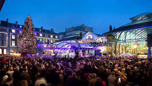 Covet Garden Piazza at night, with a crowd of people and an illuminated Christmas tree.