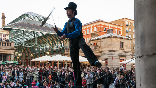 A street performer entertains the crowds in Covent Garden's Piazza, London.