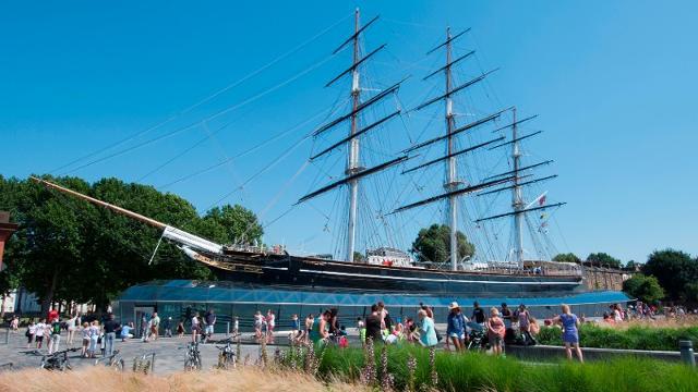 People enjoy the sunshine outside the Cutty Sark ship in Greenwich.