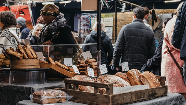 Market stall in Greenwich selling artisan bread arranged in wooden boxes.