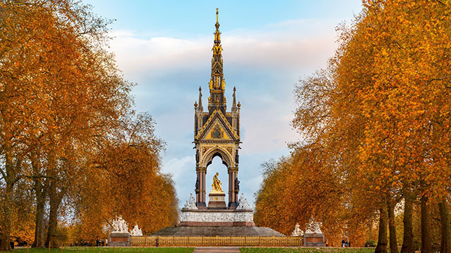 The Albert Memorial in Kensington Gardens surrounded by trees covered in red autumn leaves.