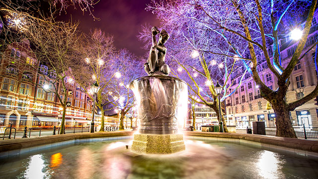 The Venus fountain on Sloane Square illuminated in colourful lights at night.