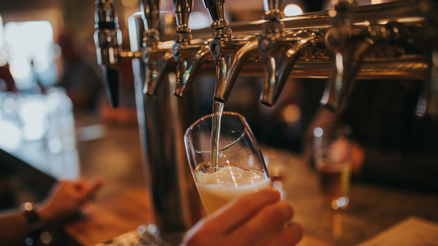 A pint is held by a hand as it is being poured.
