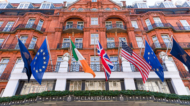 Red-brick facade of Claridge's hotel in London's Mayfair, adorned with international flags.