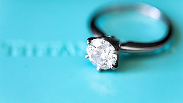 A silver diamond ring in top of a blue Tiffany box
