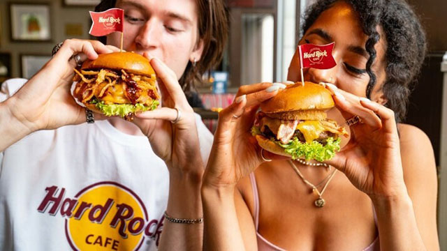 A man wearing a Hard Rock Cafe t-shirt with a woman eating American-style burgers