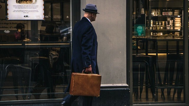 A man walking along the street with a suitcase