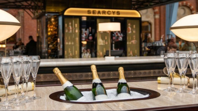 Searcys Champagne bar top with three champagne bottles submerged in ice, surrounded by empty champagne glasses