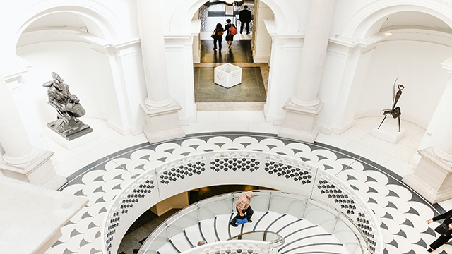 A man walks up a set of white stairs of the Tate Britain
