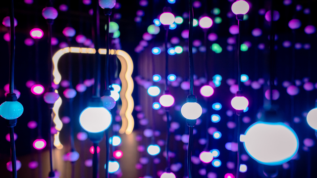 A light installation in a dark room with multi-coloured lightbulbs at Twist Museum
