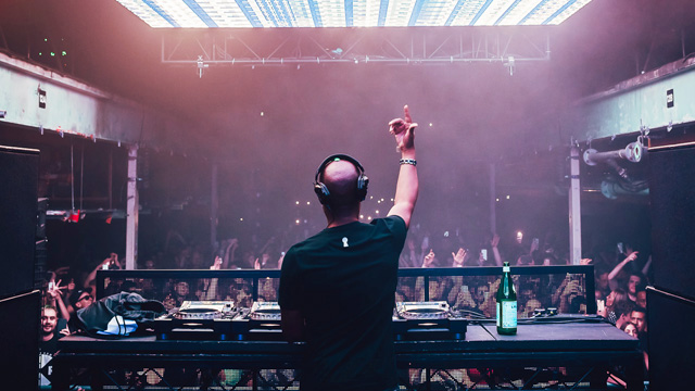 DJ at the decks in front of a crowd at Printworks London