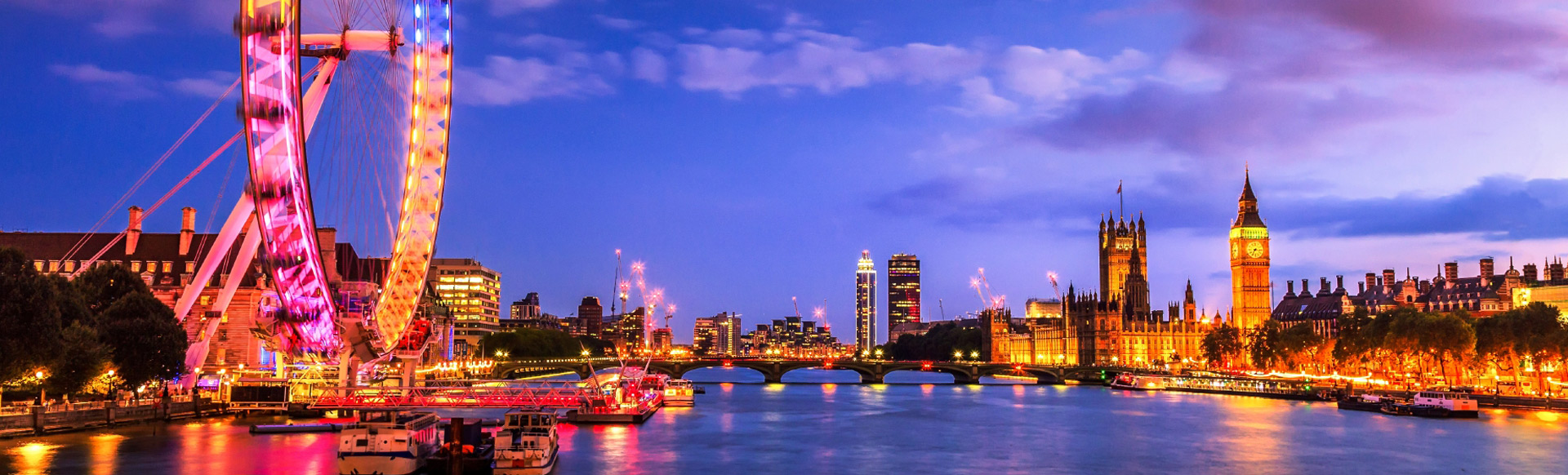 Views over the river Thames with the Houses of Parliament and the London Eye lit up, as darkness begins to fall over the capital.