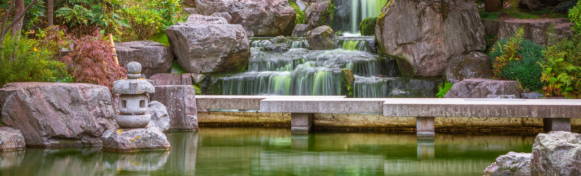 A waterfall cascades down rocks into a pool, surrounded by acers and other foliage, at the Kyoto Garden in Holland Park.