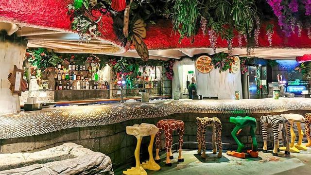 A jungle-inspired bar with animal stools and giant butterflies and plants hanging from the ceiling. 