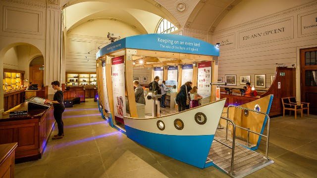 The interior of the Bank of England Museum which features a boat-shaped structure in the middle of the room containing interactive exhibits.