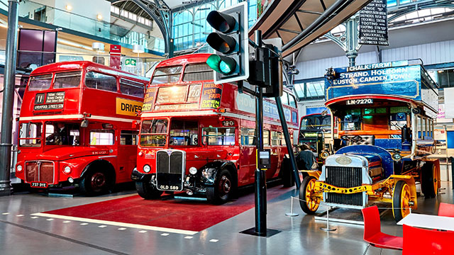 Two red London buses and an older bus inside the London Transport Museum in Covent Garden.