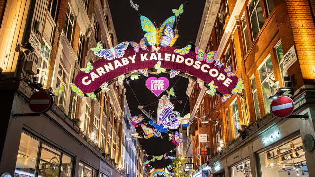 Weihnachtslichterinstallation über der Carnaby Street in London. Eine Reklame mit den Worten "Carnaby Kaleidoscope". 