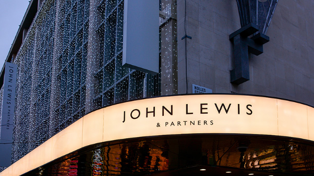 Lit-up exterior signage at John Lewis on a grey day in London