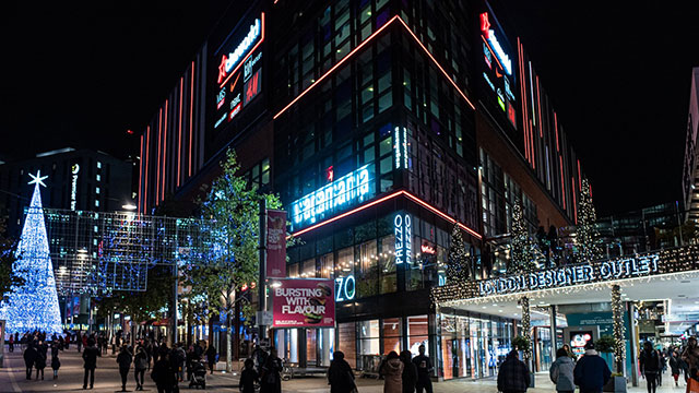 The exterior of the shops illuminated at the London Designer Outlet Wembley at night time