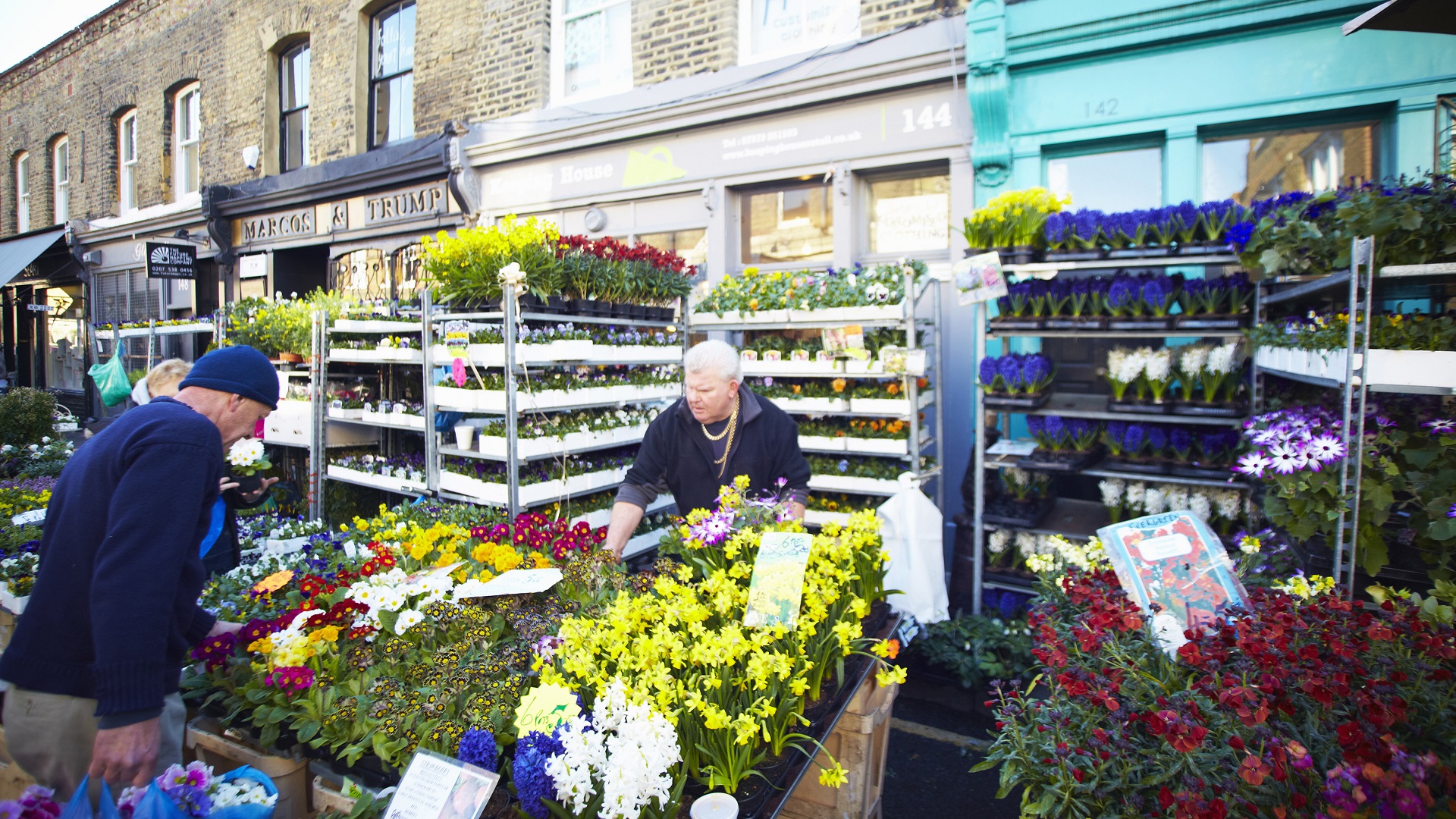 Market seller surrounded by daffodils and other plants at Columbia Road Flower Market