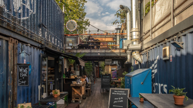 Shops inside blue shipping containers on a sunny day at Pop Brixton, London