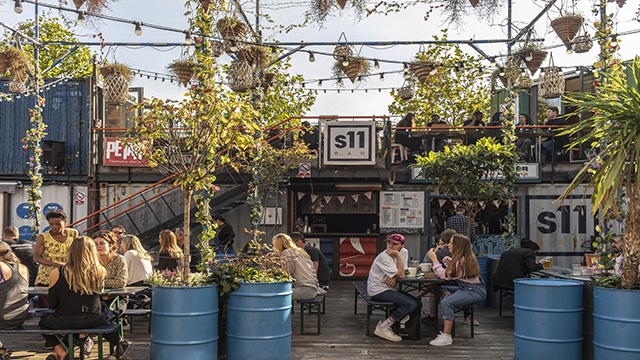 Shops and bars inside shipping containers on a sunny day at Pop Brixton, London