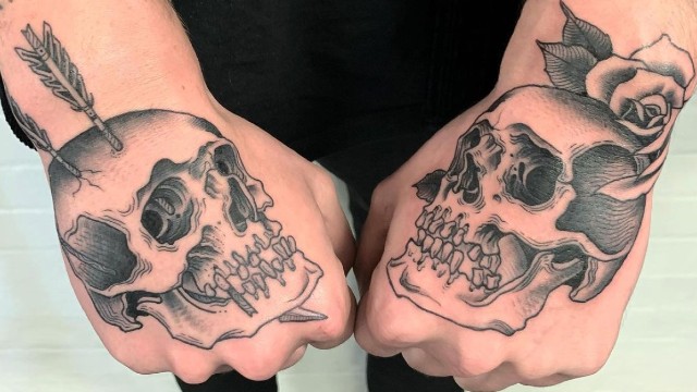 A man's hand skull tattoos seen close-up.