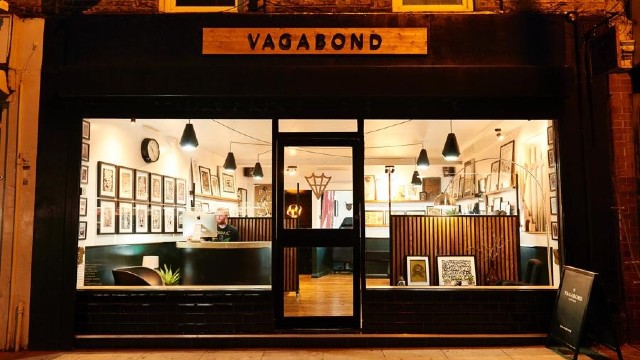Vagabond Tattoo Studio's lit-up shopfront at night.
