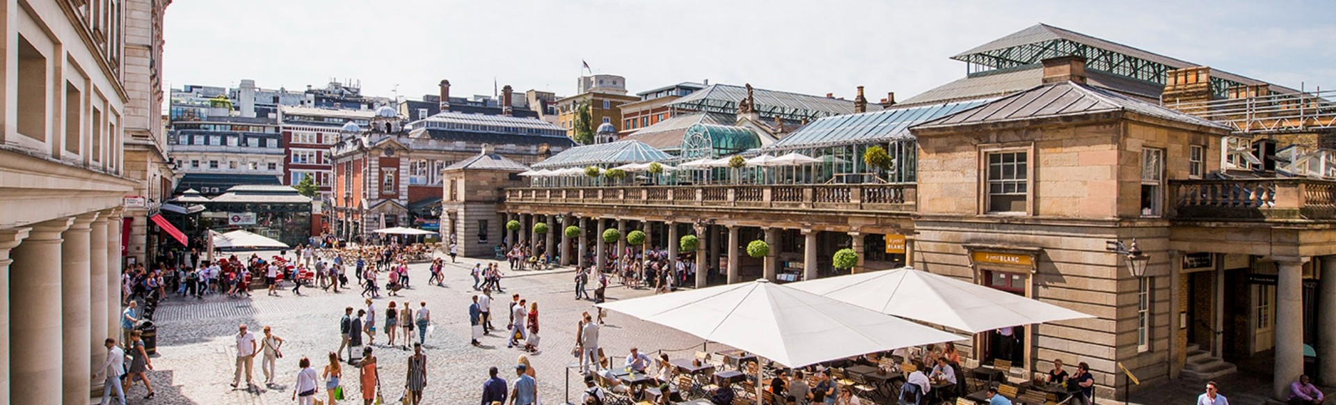 People walking in Covent Garden Piazza on a sunny day.