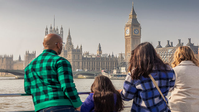 A family of four observe Big Ben and the Houses of Parliament from a cruise on the Thames.