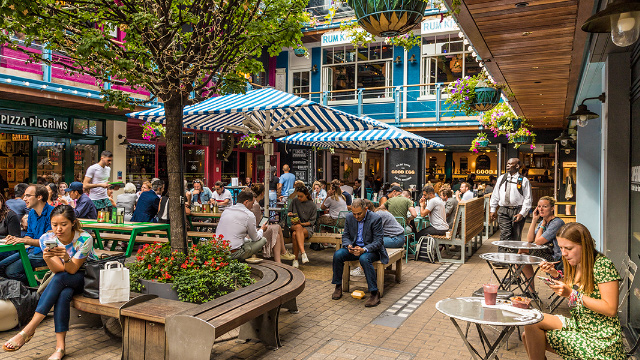 London Carnaby's Kingly Court with people sitting at outside tables enjoying food and drinks on a summer's day.