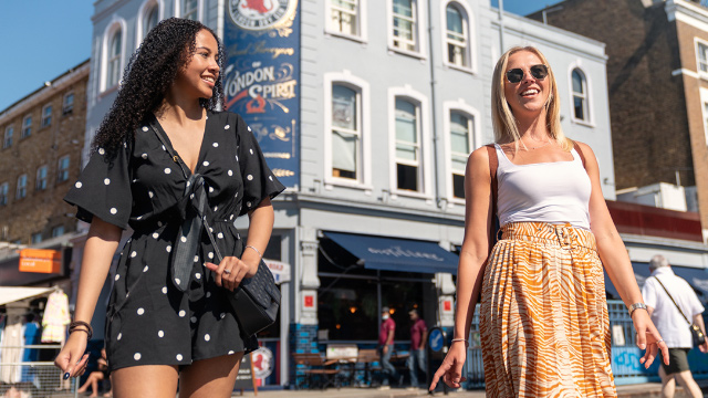 Two young women walking on Portobello Road in west London’s Notting Hill on a summer's day.