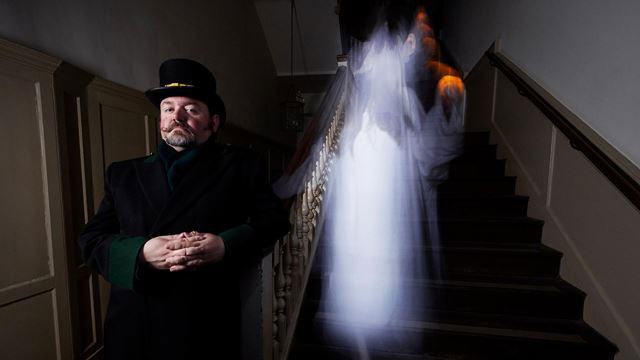 A warden stands with a ghostly apparition behind him