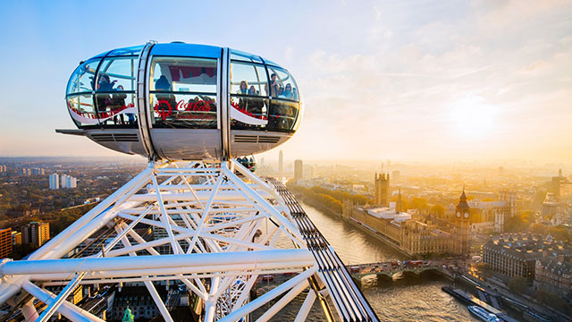 People in a London Eye pod admiring the views of London, with the river Thames and Houses of Parliament below