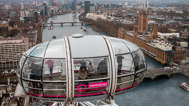 An aerial view of a pod on the London Eye with the river Thames, Houses of Parliament and Big Ben in the background on a cloudy day in London.