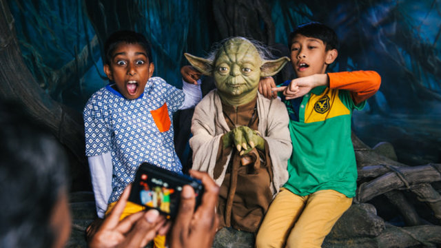 Two children pose with a wax figure of Yoda at Madame Tussauds London.