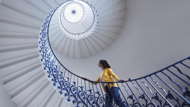 A woman climbs up Queen's House's white and blue Tulip Staircase in Greenwich.