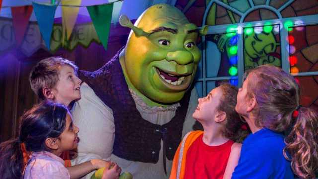 A group of four children amazed at seeing and talking to Shrek at Shrek's Adventure! London.