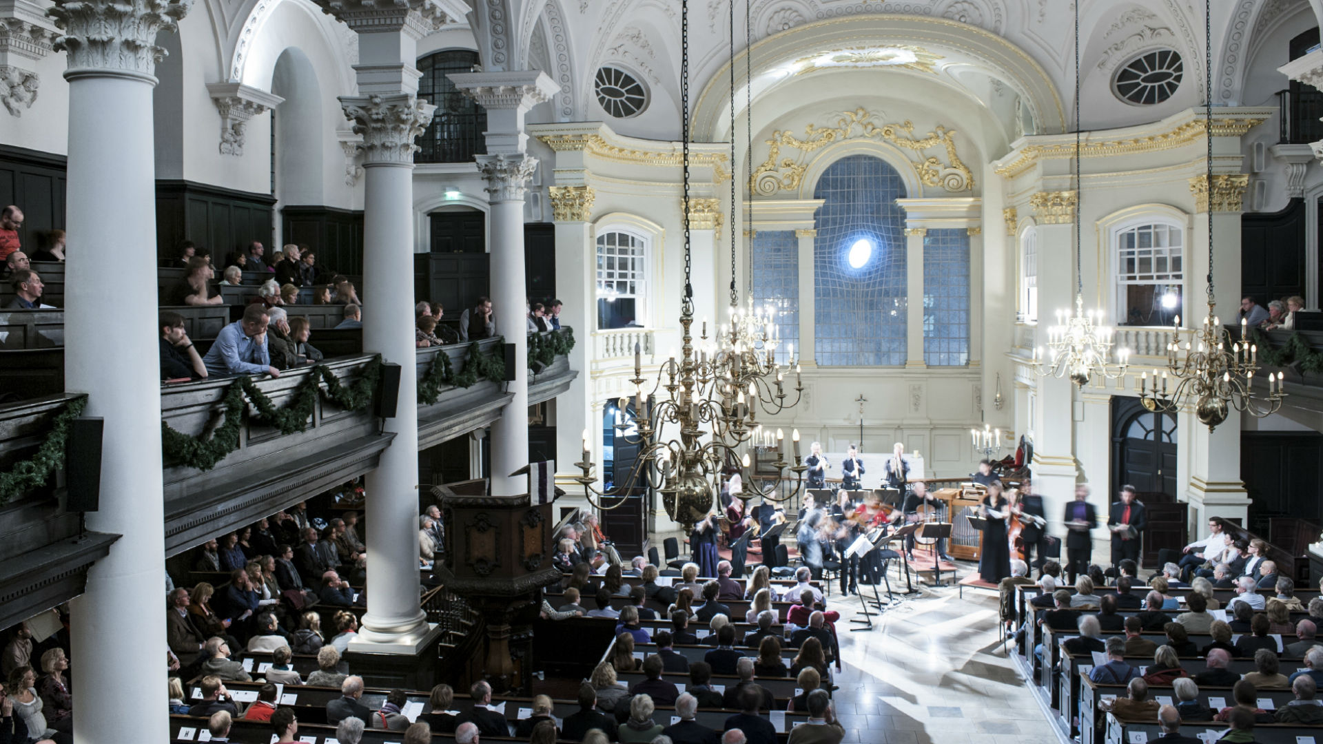 A photo of a crowd in the St Martin-in-the-Fields Church in the evening, attending a ceremony. 