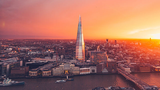 A view of the London skyline with the Shard towering in the centre of the photo, with the sun setting behind it.
