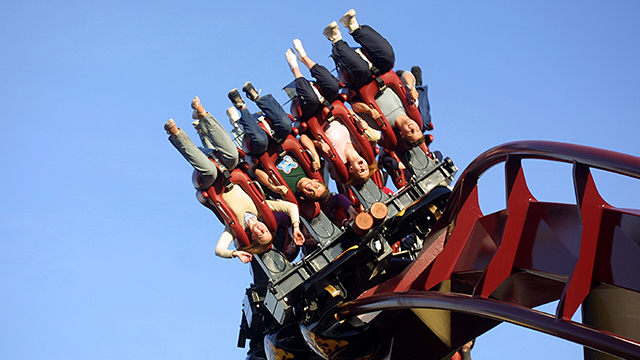 People hanging upside down as the Nemesis Inferno ride goes upside down on its red rails.