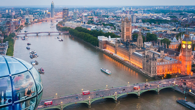 The corner of a London Eye pod in the air that overlooks the river and Houses of Parliament.