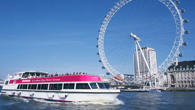 London Eye river cruise boat gliding on the river Thames with the London Eye in the background.